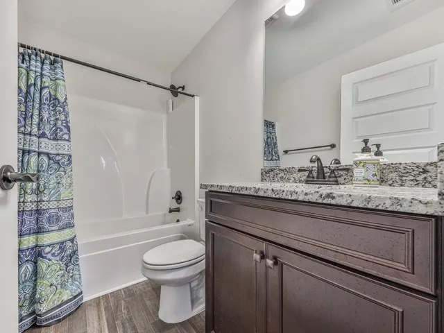 a bathroom with a granite countertop sink a toilet and shower