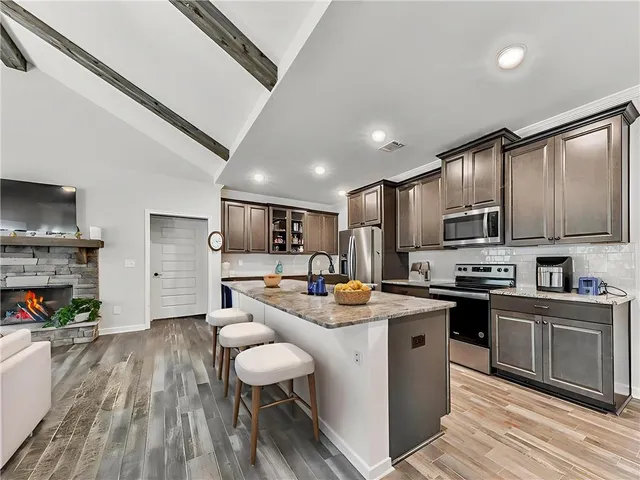 a kitchen with kitchen island granite countertop lots of counter top space a sink appliances and cabinets