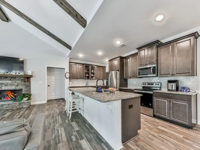 a kitchen with stainless steel appliances granite countertop a sink dishwasher stove top oven and cabinets with wooden floor