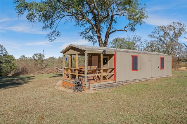a view of a wooden house with a small yard and wooden fence