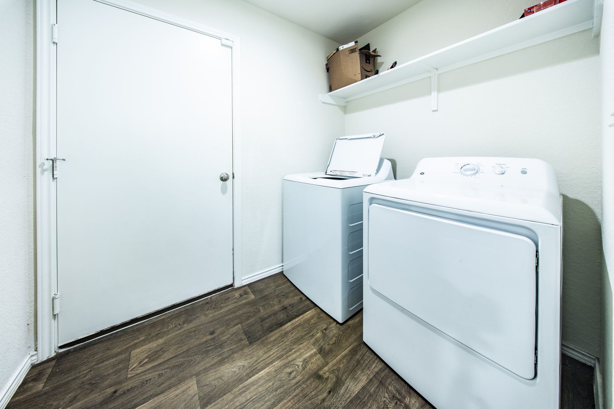 14903 Tuff Road Manor, TX 78653 - Photo 19 of 25 Functional laundry room featuring robust wood flooring and convenient overhead shelving.