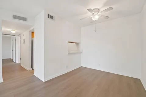 an empty room with wooden floor and ceiling fan