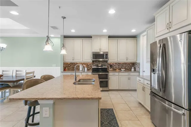 a kitchen with granite countertop a refrigerator a stove a sink and white cabinets with wooden floor