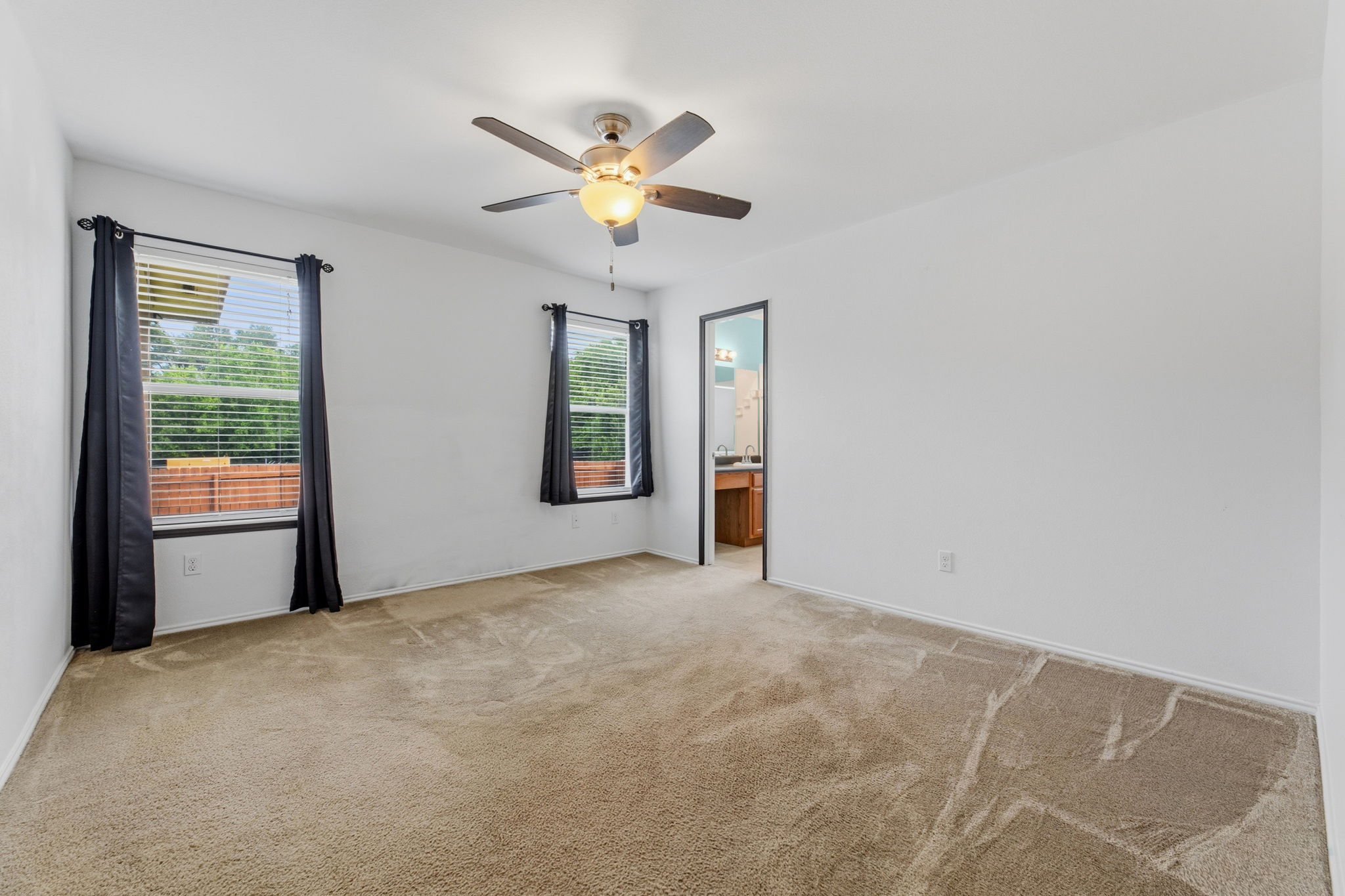 12601 Waynespur Lane Elgin, TX 78621 - Photo 26 of 38 Comfortable carpeted bedroom with multiple windows, featuring a practical ceiling fan for year-round comfort.