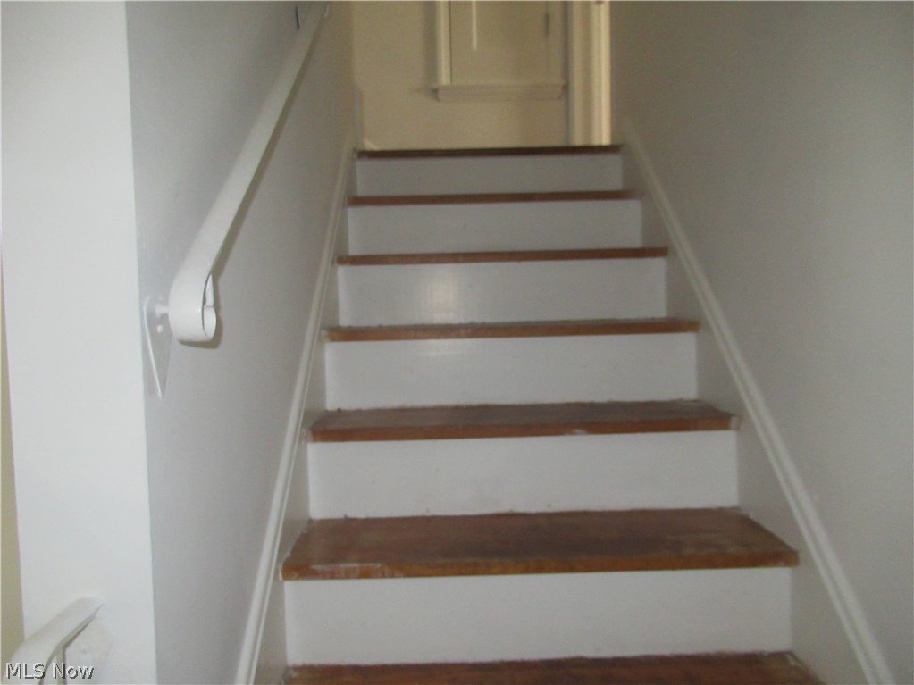 5095 Edenhurst Road Lyndhurst, OH 44124 - Photo 14 of 24 Staircase featuring wood-finish treads, white risers, and a wall-mounted handrail