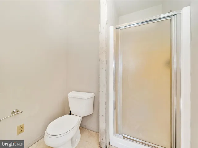 a view of a hallway with wooden floor and a bathroom