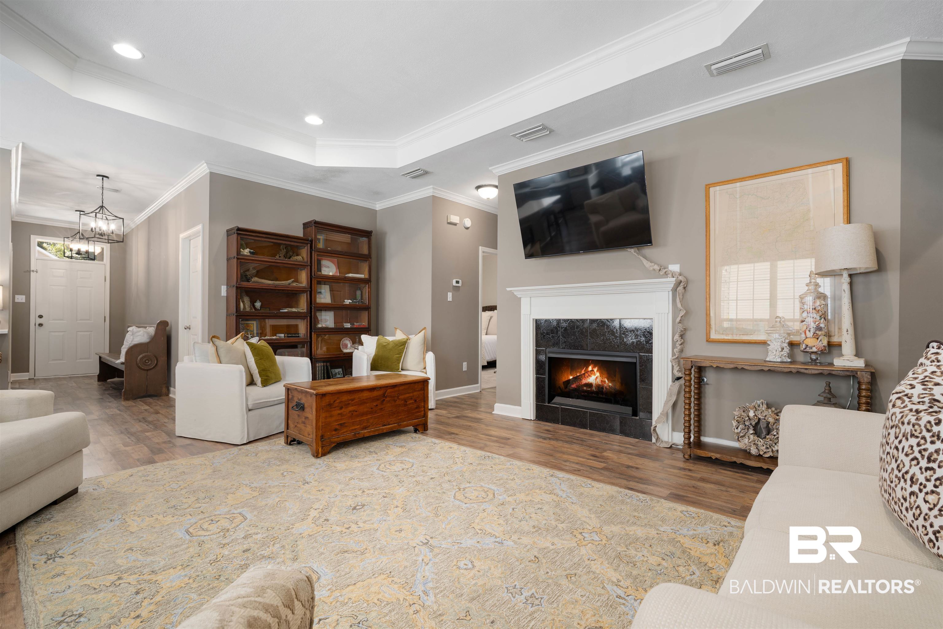 27288 Parker Lane Daphne, AL 36526 - Photo 2 of 29 Living area with a fireplace, wood finished floors, crown molding, a tray ceiling, and a chandelier