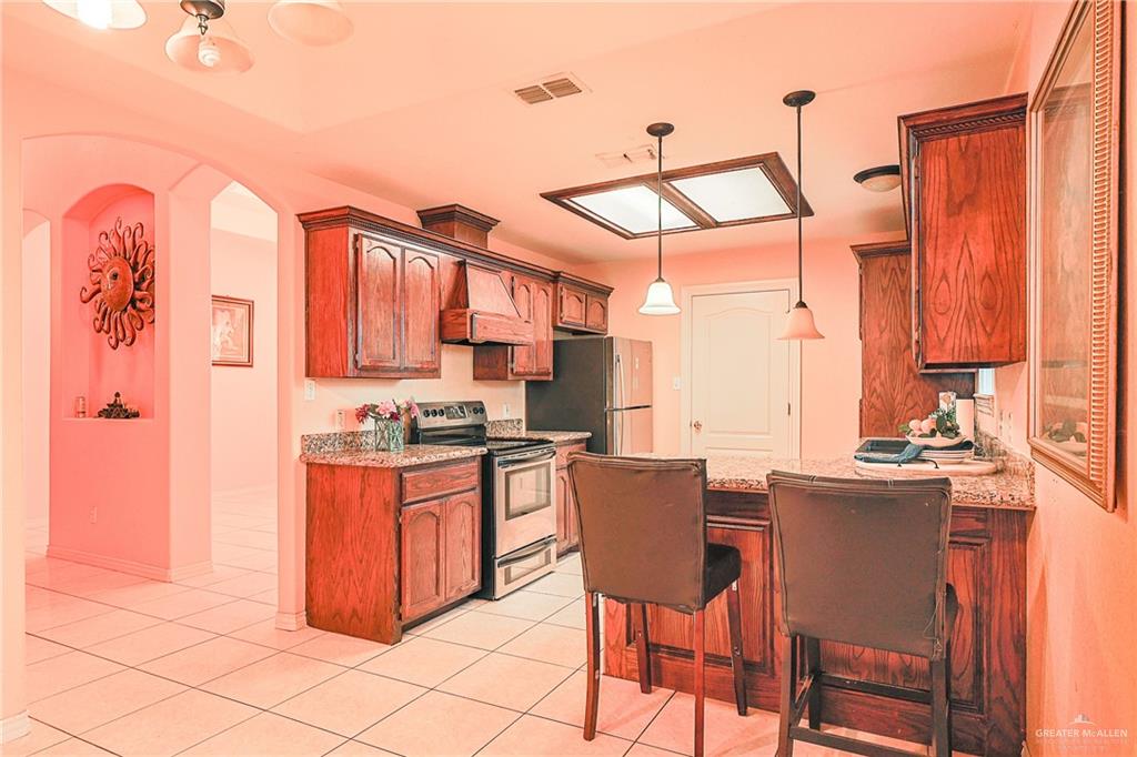 713 West 24th Place Mission, TX 78574 - Photo 12 of 36 a kitchen with stainless steel appliances granite countertop a stove a sink dishwasher and a refrigerator with wooden cabinets