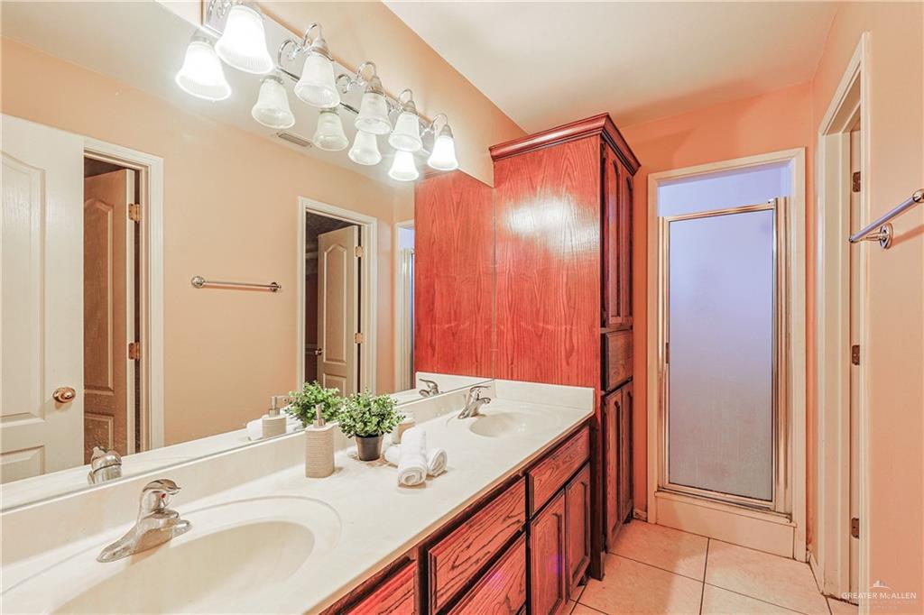 713 West 24th Place Mission, TX 78574 - Photo 17 of 36 a bathroom with a granite countertop sink a large mirror and a shower