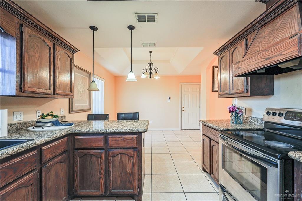 713 West 24th Place Mission, TX 78574 - Photo 10 of 36 a kitchen with stainless steel appliances granite countertop a sink a stove and a wooden floors