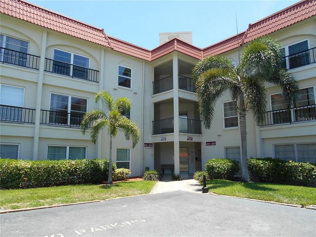 2700 Bayshore Boulevard, Unit 4103 Dunedin, FL 34698 - Photo 1 of 1 a front view of a building with garden and trees
