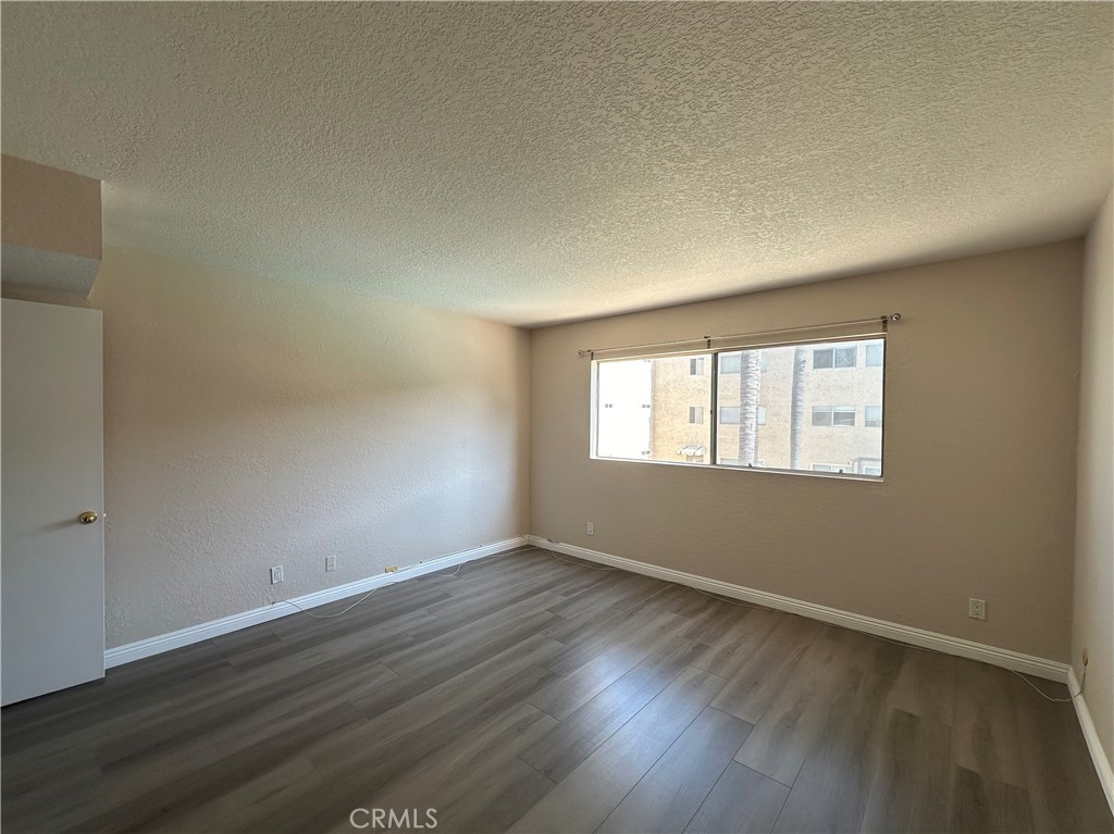 2386 East Del Mar Boulevard, Unit 203 Pasadena, CA 91107 - Photo 19 of 28 a view of an empty room with wooden floor and a window