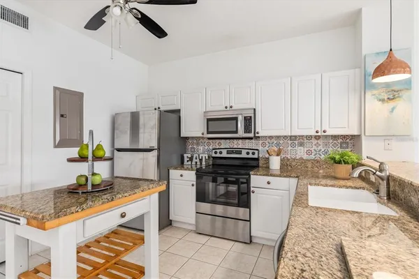 a kitchen with stainless steel appliances granite countertop a stove top oven a sink a counter space and cabinets