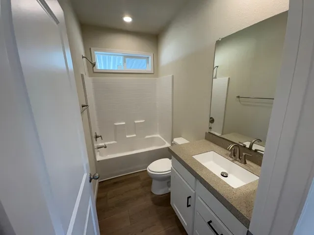 a bathroom with a granite countertop toilet a sink and a mirror
