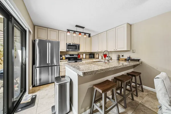 a kitchen with stainless steel appliances granite countertop a refrigerator a stove a sink and a microwave