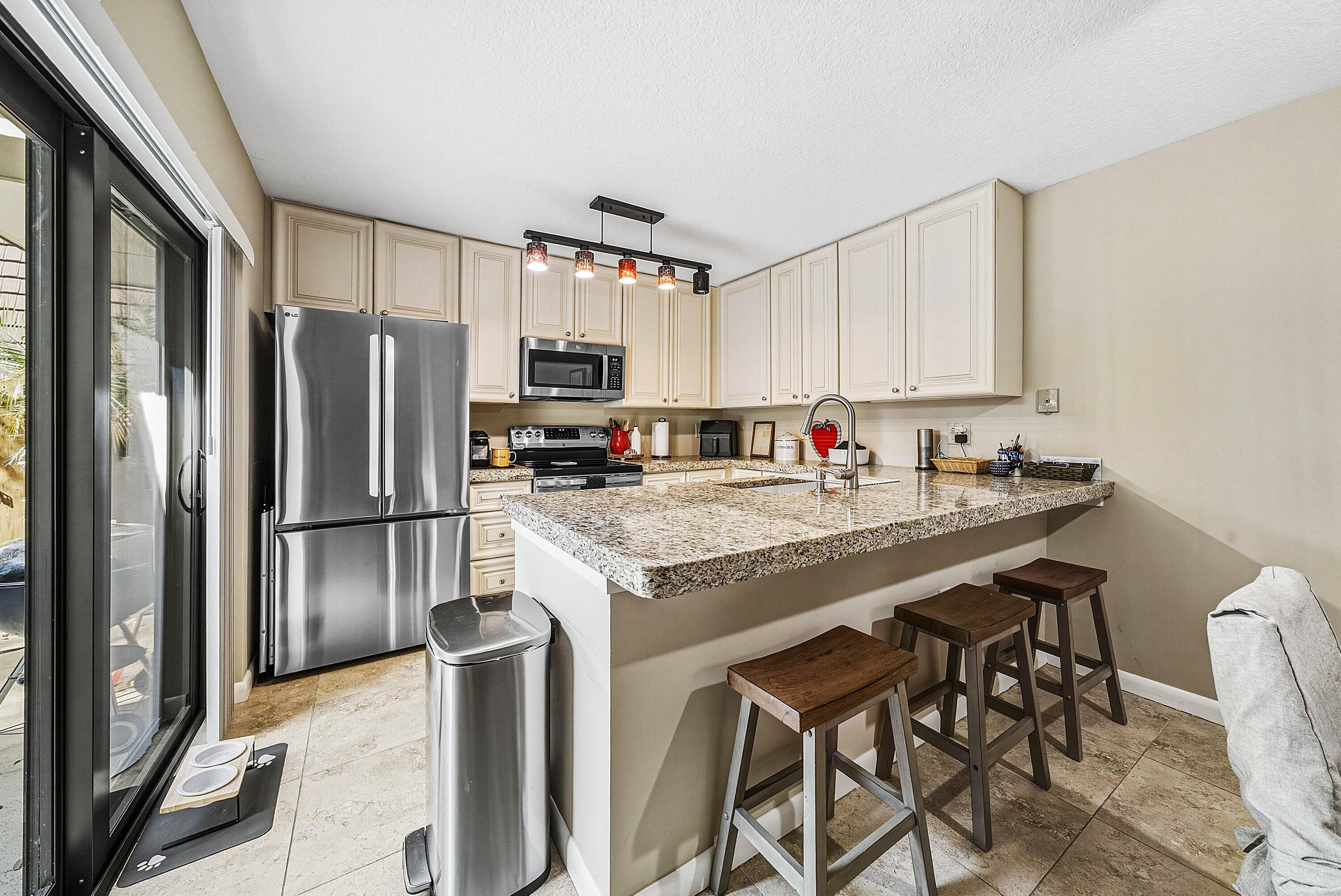 2715 27th Court Jupiter, FL 33477 - Photo 14 of 22 a kitchen with stainless steel appliances granite countertop a refrigerator a stove a sink and a microwave