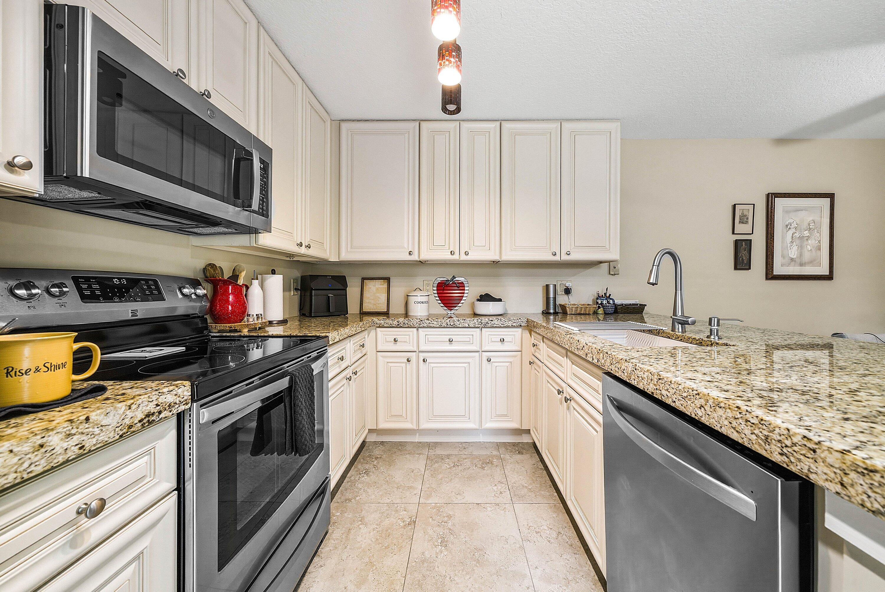 2715 27th Court Jupiter, FL 33477 - Photo 10 of 22 a kitchen with stainless steel appliances granite countertop a sink stove microwave and cabinets