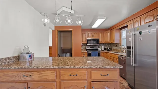 a kitchen with stainless steel appliances granite countertop a refrigerator a stove and a sink