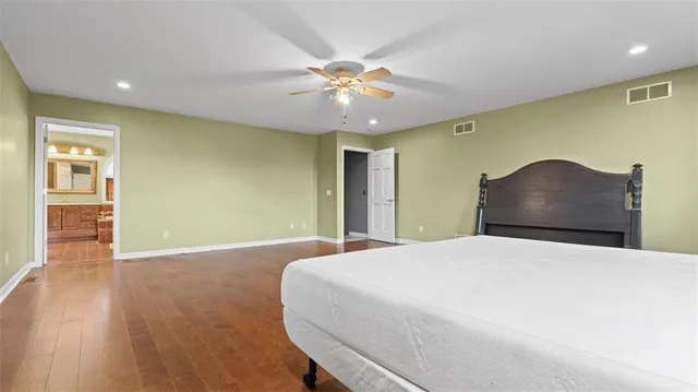 a bedroom with a large bed and wooden floor