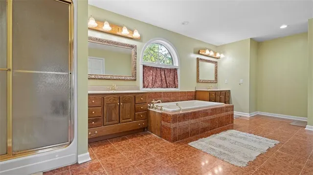 a spacious bathroom with a tub sink and mirror