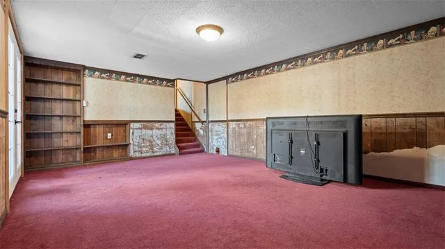 a view of an empty room with furniture and staircase