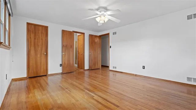 a view of an empty room with window and wooden floor