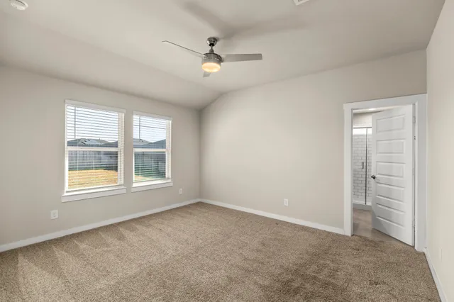 an empty room with chandelier fan and windows