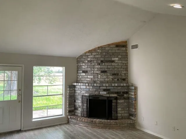 an empty room with windows and fireplace