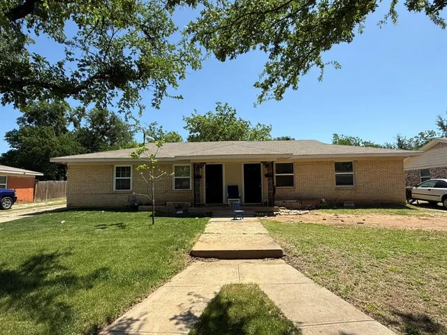 a front view of house with yard and trees in the background