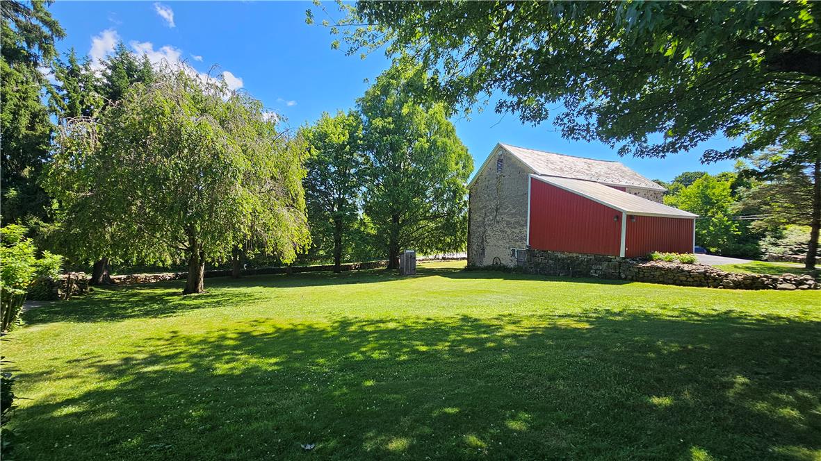585 Buttermilk Road Hellertown, PA 18055 - Photo 72 of 82 A spacious green lawn surrounds a classic barn with red siding under a clear blue sky.