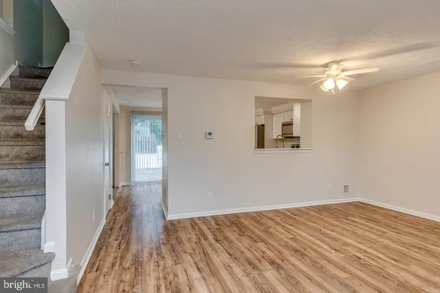a view of a room with wooden floor and a ceiling fan