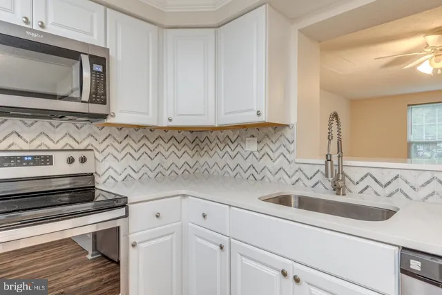 a kitchen with stainless steel appliances granite countertop white cabinets and a sink
