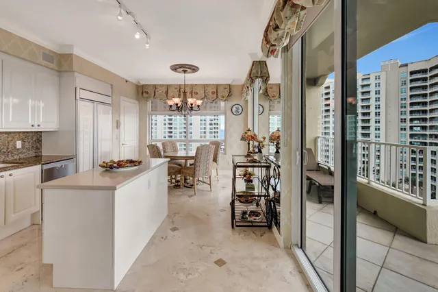 a dining room with furniture a chandelier and kitchen view