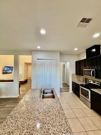 a large kitchen with stainless steel appliances kitchen island granite countertop a refrigerator and a stove top oven