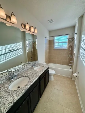 a bathroom with a granite countertop sink a toilet a mirror and bathtub