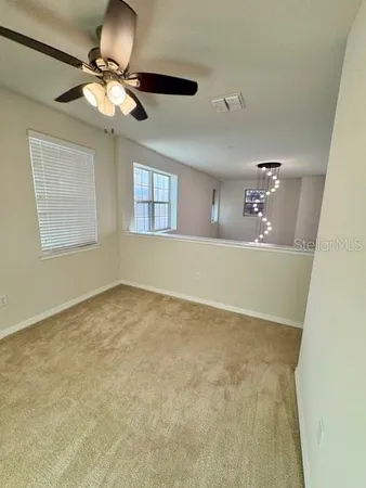 a view of an empty room and chandelier fan
