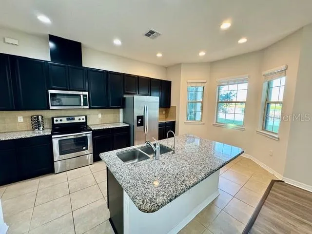 a kitchen with stainless steel appliances granite countertop a sink dishwasher and a stove top oven with wooden floor