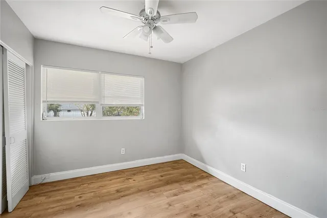 an empty room with a window and a ceiling fan