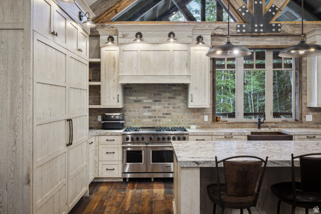 1667 West Tollgate Cyn Road Coalville, UT 84017 - Photo 25 of 61 Gourmet kitchen featuring a professional-grade stainless steel range, light wood-finish cabinetry, stone countertops, a brick-patterned backsplash, and rich wood-finish flooring