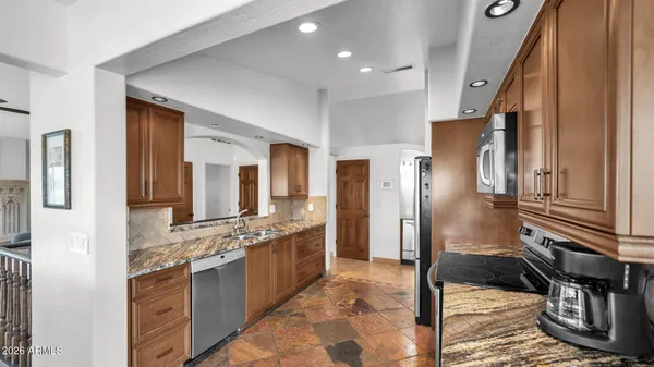 a kitchen with stainless steel appliances granite countertop a refrigerator a stove and a sink with large window