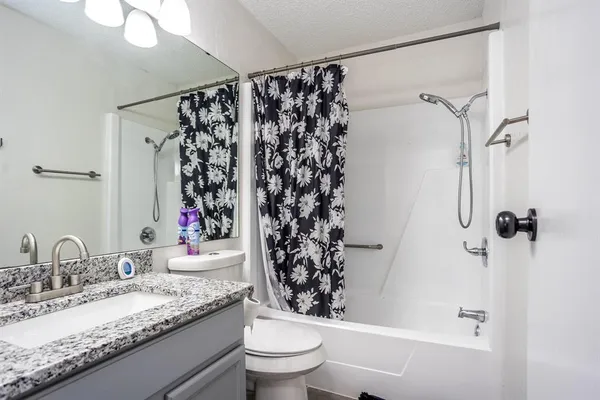 a bathroom with a granite countertop sink toilet and shower