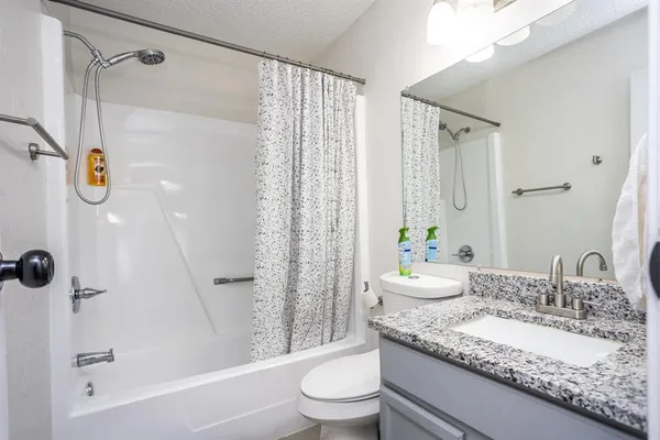 a bathroom with a granite countertop sink toilet and shower
