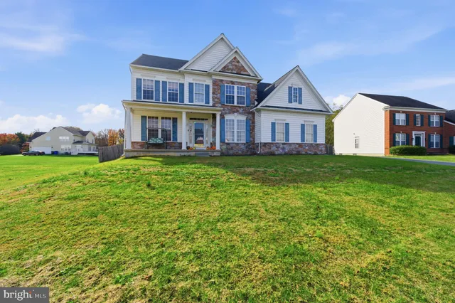 a view of a house next to a big yard and large trees
