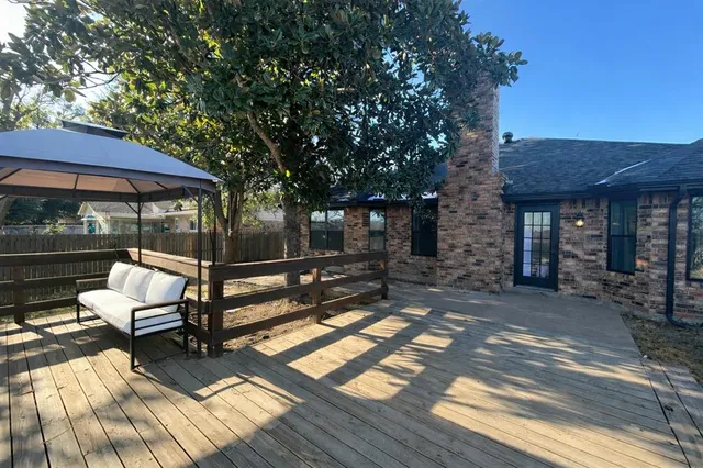 a view of a patio with table and chairs under an umbrella with wooden floor