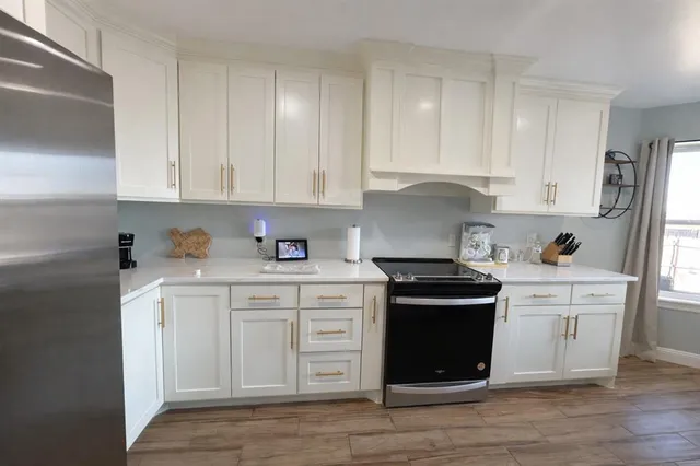 a kitchen with stainless steel appliances granite countertop a stove and white cabinets