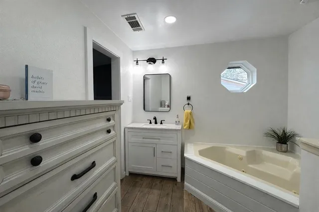 a bathroom with a tub sink and mirror