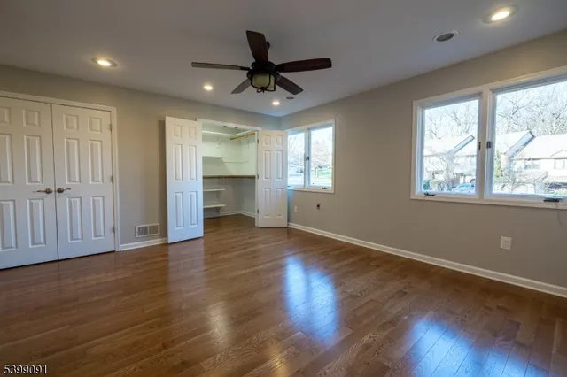 a view of empty room with wooden floor and fan