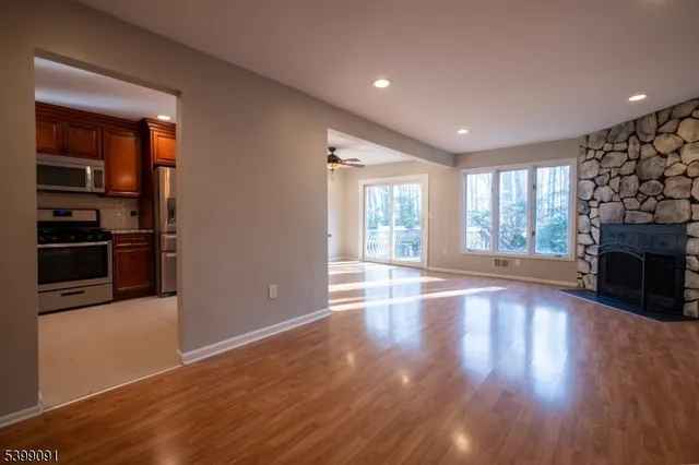 an empty room with wooden floor fireplace and windows
