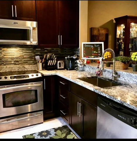 a kitchen with stainless steel appliances kitchen island granite countertop a stove microwave and oven