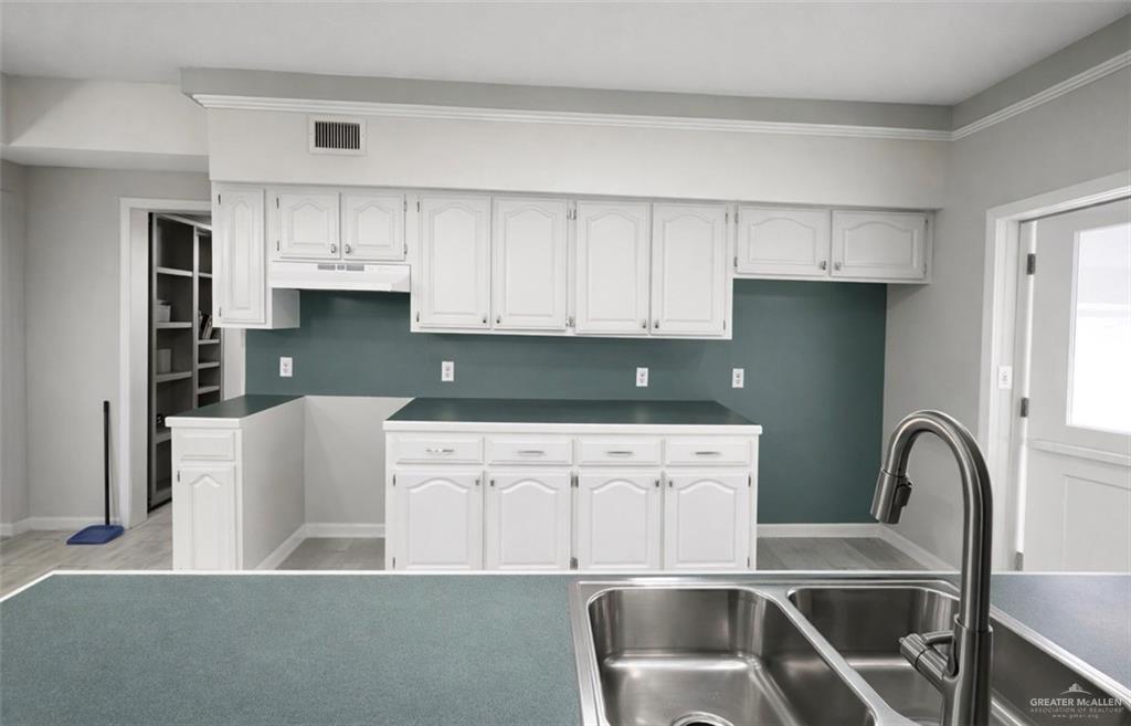 1403 North Shary Road Mission, TX 78572 - Photo 4 of 9 Kitchen with white cabinetry and baseboards